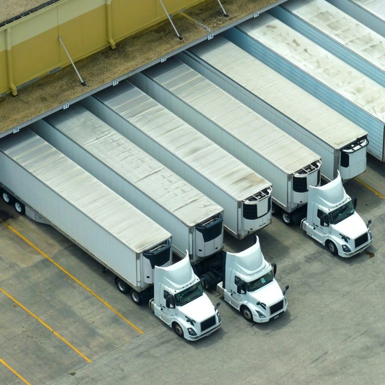 Luftaufnahme von Lkw, die in einer Lagerhalle geparkt sind.